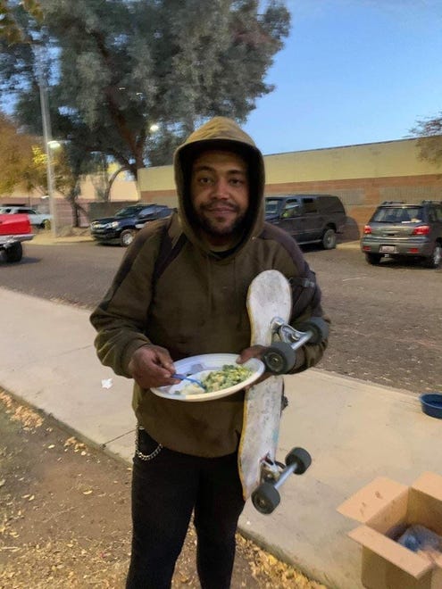 Sean Bickings poses for a picture holding a skateboard and a dinner plate at Jaycee Park in Tempe.