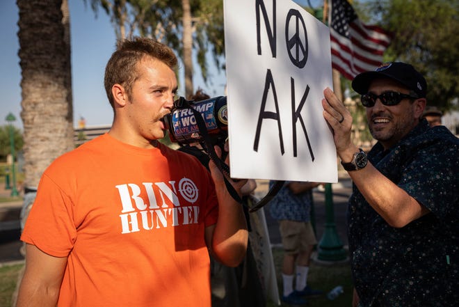 Ethan Schmidt Crockett, (left) a gun rights activist speaks through a megaphone in an attempt to interrupt the March for Our Lives demonstration outside the Arizona Capitol on June 11, 2022, in Phoenix. Hundreds of people gathered as part of a nationwide demonstration calling for stricter gun laws in response to recent mass shootings.