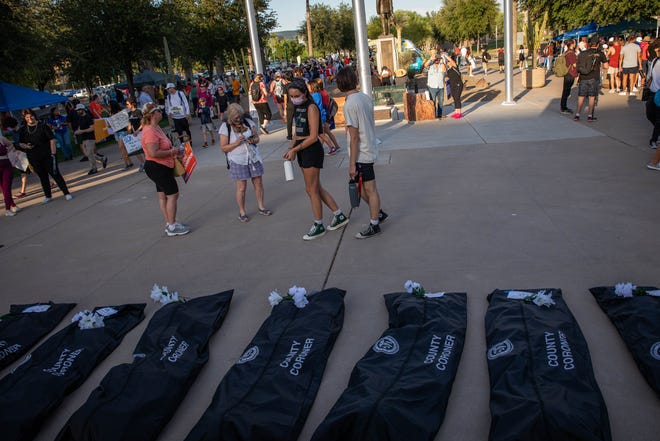 Demonstrators with the March for Our Lives walk past body bags laid outside the Arizona Capitol on June 11, 2022, in Phoenix as a reminder of the lives lost to gun violence. Hundreds of people participated in a nationwide demonstration calling for stricter gun laws in response to recent mass shootings.