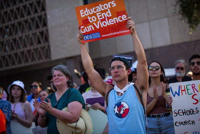 Alex Shawver (center) holds a sign in support of stricter gun legislation outside the Arizona Capitol on June 11, 2022, in Phoenix as hundreds of people take part in a nationwide demonstration in response to recent mass shootings.