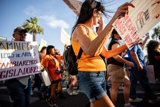 People carried homemade signs as they marched to Arizona Capitol on June 11, 2022, in Phoenix to demand stricter gun laws in response to recent mass shootings.