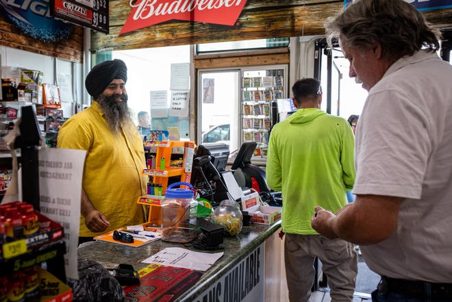 Customers prepare to pay for gas as one of the owners of the pump Jaswinder Singh, left, greets them inside the store on the corner of 20th Street and Osborn Road in Phoenix on June 21, 2022.