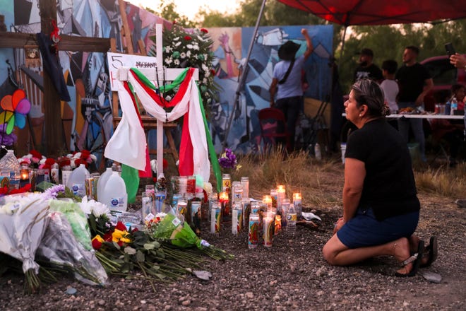 Una mujer se arrodilla frente a una cruz en un sitio conmemorativo en San Antonio, Texas, el 29 de junio de 2022. El sitio está dedicado a 53 migrantes que murieron por enfermedades relacionadas con el calor en un semirremolque abandonado en el suroeste de San Antonio el 27 de junio de 2022.