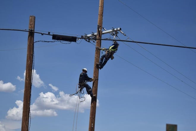 APS workers restringing wire across the road on highway 191 and Leake Road in Douglas after a storm caused major power outages.