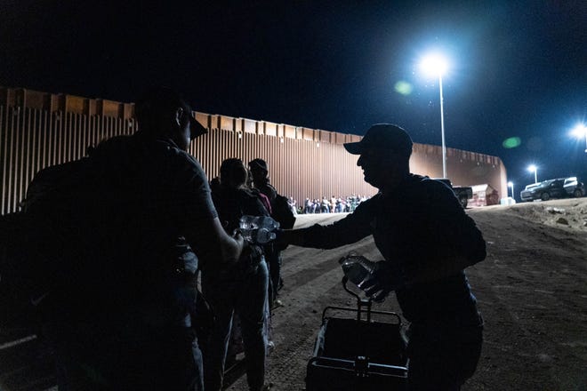 Fernando Quiroz, Yuma resident and director of the AZ-CA Humanitarian Coalition, right, hands water to migrants and asylum seekers detained by U.S. Border Patrol agents after crossing the U.S.-Mexico border in Yuma County, Arizona, nearby the Cocopah Indian Tribe's reservation on July 28, 2022.