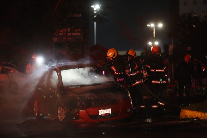 Bomberos apagan un vehículo incendiado por presuntos criminales el 9 de agosto de 2022, en Zapopan (México).