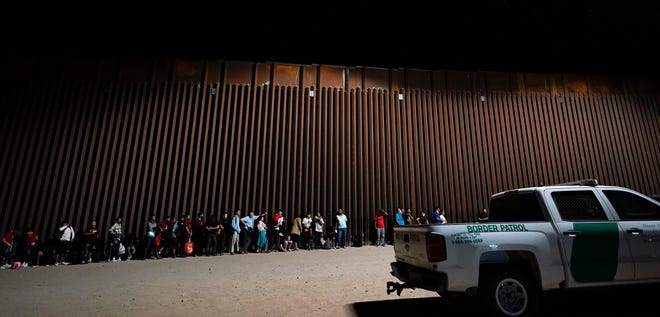 Migrants cross the border into Yuma on Aug. 23, 2022, despite a shipping container wall.