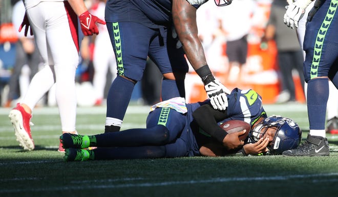 Geno Smith #7 of the Seattle Seahawks stays on the ground after being sacked against the Arizona Cardinals during the third quarter at Lumen Field on October 16, 2022, in Seattle, Washington.