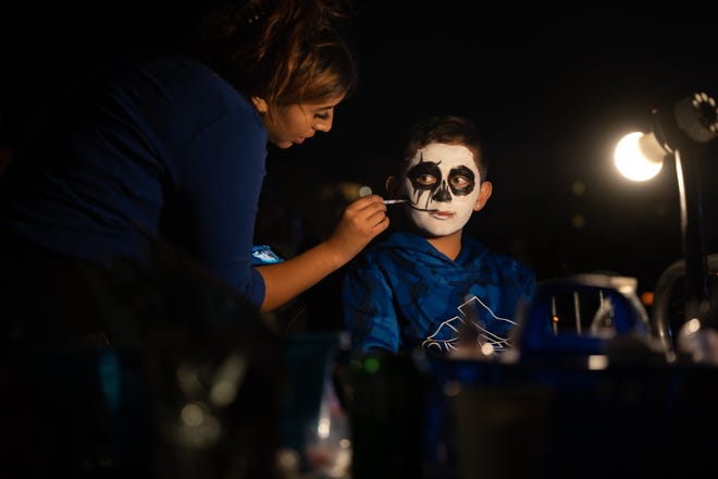 Gallego Face Painting artist Jasalyn Hong face paints Armann Diaz at the 33rd Annual All Souls Procession in Tucson on Nov. 6, 2022. The procession is not a Day of the Dead-themed celebration, but an opportunity for community members to honor the dead through any tradition, said event parent organization and nonprofit Many Mouths One Stomach.