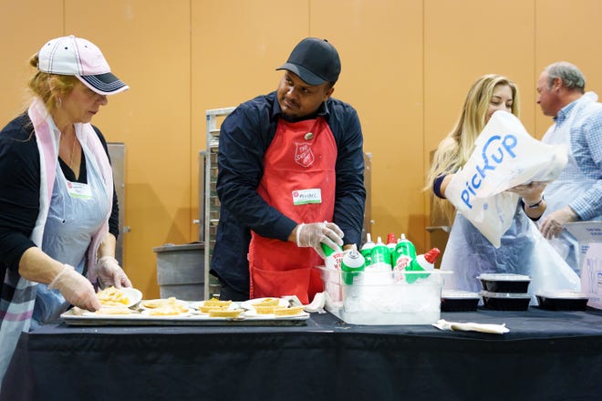 Michael Hall (center) helps serve dessert at the Salvation Army's Thanksgiving event at the Phoenix Convention Center on Nov. 24, 2022.