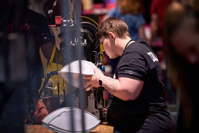 A Wilson employee begins sewing together the shell of a football during the Super Bowl Experience at the Phoenix Convention Center on Feb. 5, 2023.